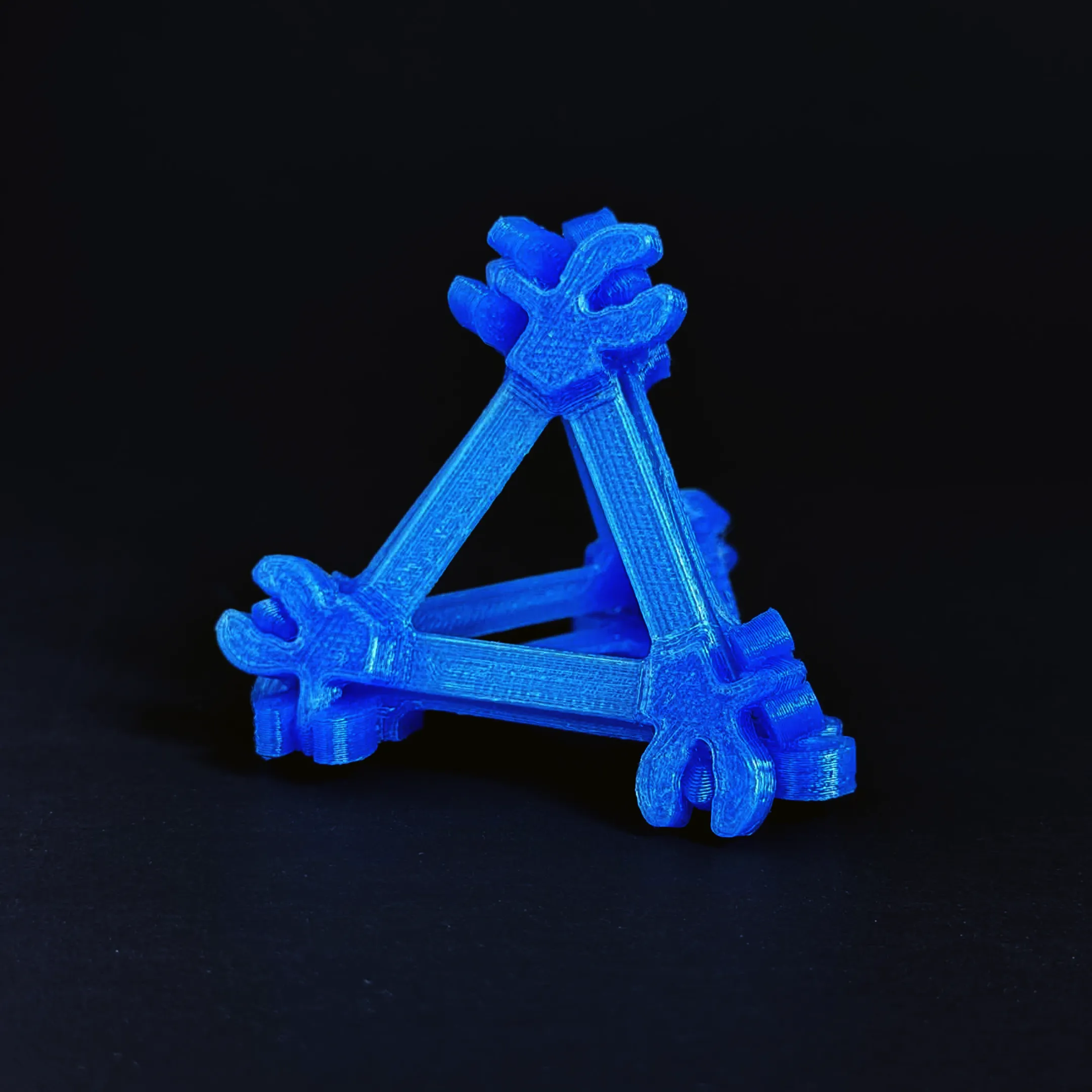 A tetrahedral Compliagon assembly with blue connection points and crisp triangular edges.